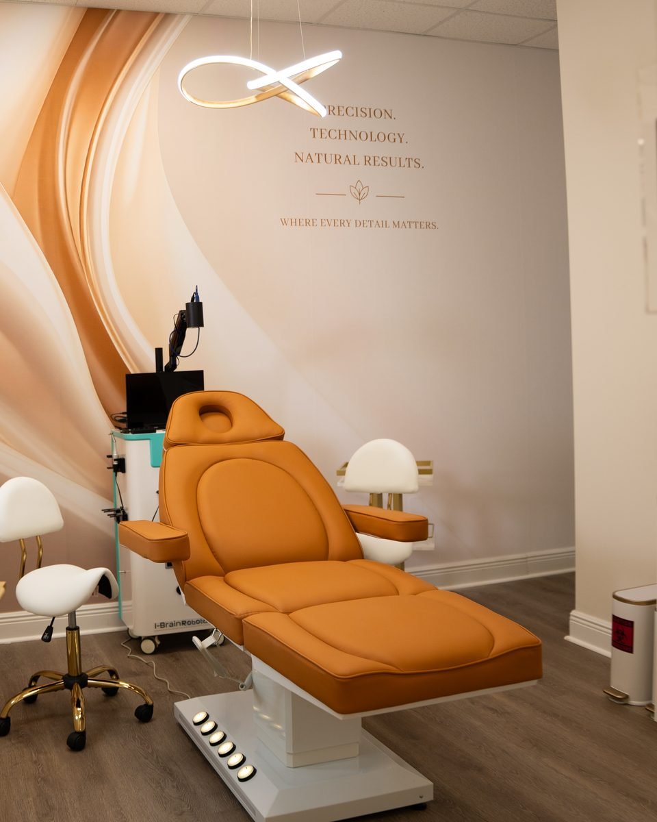 Treatment room at The Edit with a caramel treatment chair under a silk-toned mural that reads Precision, Technology, Natural Results